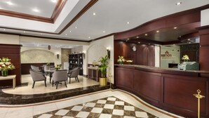 Un vestíbulo de hotel con mostrador de recepción, zona de estar y un suelo decorado con diseño de cuadros.