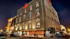 Un hotel de varios pisos con ventanas arqueadas y balcones, un letrero llamativo y una fachada bien iluminada.