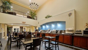 A spacious dining area with multiple tables and chairs, a kitchen counter with appliances, and a balcony with plants. - Best Western Plus Cutting Horse Inn & Suites (Weatherford)