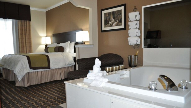 A hotel room with a large bed, a separate sofa, a bathroom with a bathtub, and a flat-screen TV. - Best Western Plus Cutting Horse Inn & Suites (Weatherford)