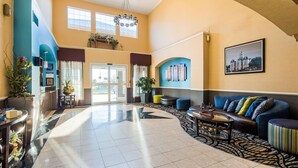 A spacious lobby with a high ceiling, a reception desk, seating area, and a large window providing natural light. - Best Western Plus Cutting Horse Inn & Suites (Weatherford)