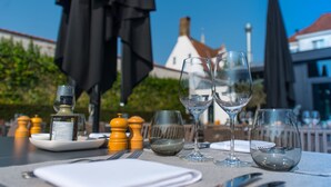 A table set for two with wine glasses, a bottle of olive oil, and salt and pepper shakers. - Hotel Montanus (Bruges)