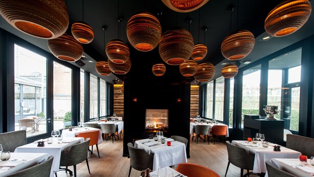 A restaurant with multiple tables, chairs, and hanging pendant lights. - Hotel Montanus (Bruges)