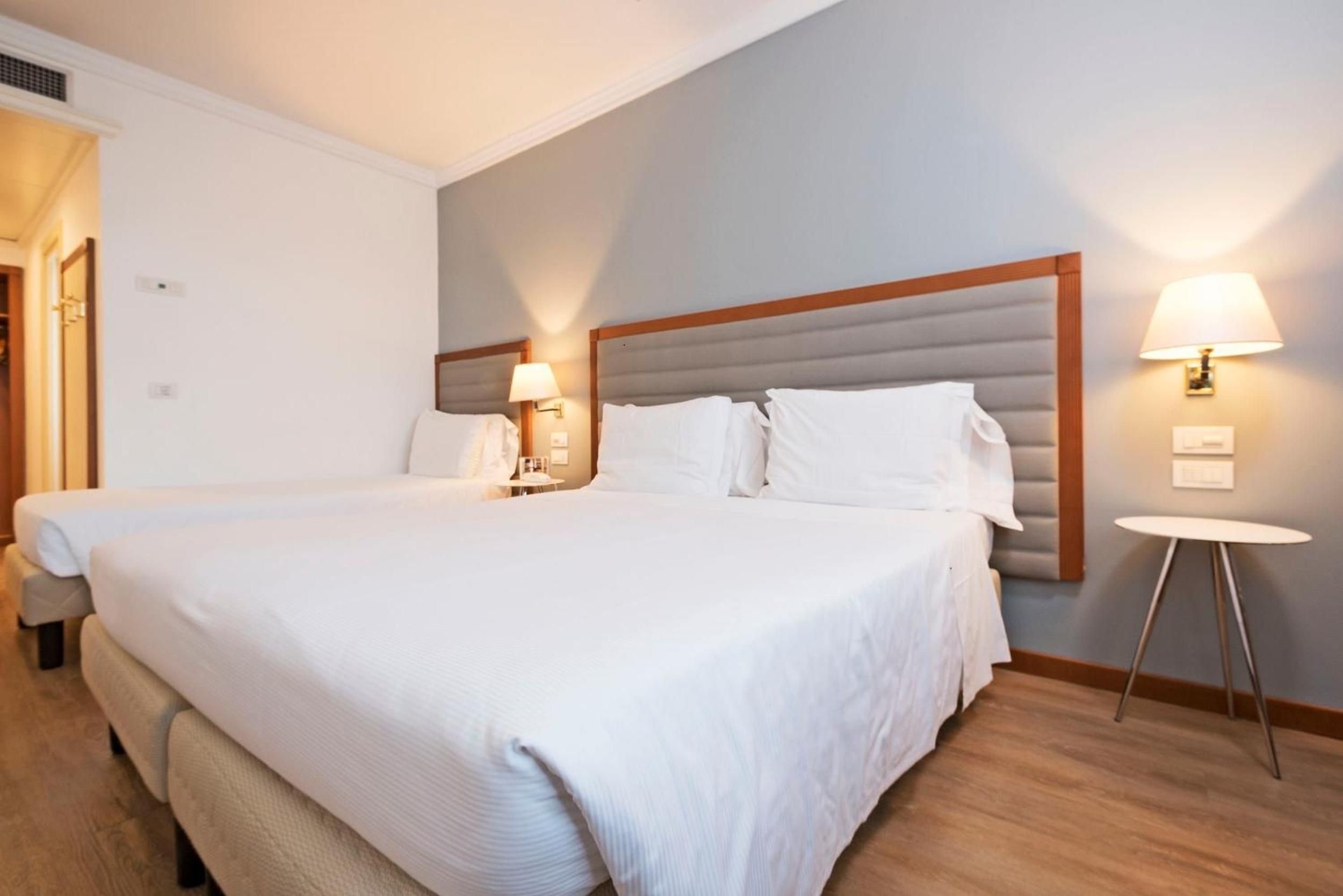Habitació d'hotel amb dos llits, una taula petita i una làmpada.