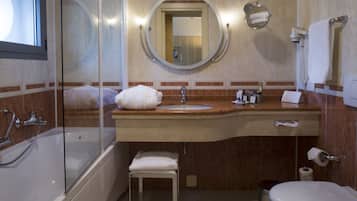 A bathroom with a glass-enclosed shower, a sink with a vanity, a toilet, and a mirror above the sink.