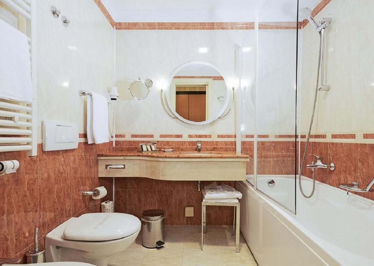 A bathroom with a toilet, sink, mirror, and shower.