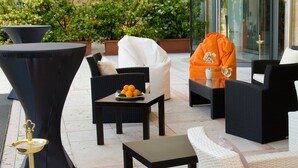 A well-appointed outdoor seating area with wicker furniture, a table with a fruit bowl, and a decorative orange bag. - Hotel Maggior Consiglio (Treviso)