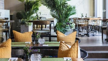 L’intérieur d’un restaurant se caractérise par de hauts plafonds, des plantes suspendues et un mélange de tables et de chaises.