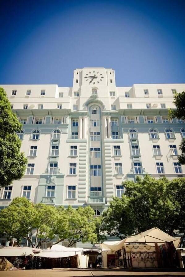 Un edificio grande y blanco con una torre de reloj, numerosas ventanas y una entrada central.