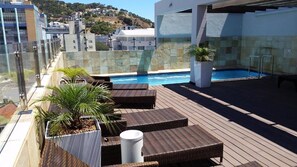 Relax by the pool on this rooftop terrace, surrounded by lush greenery and offering stunning views of the surrounding landscape.
