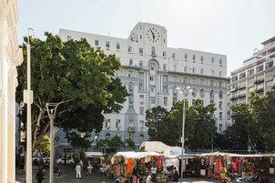 A market area with stalls and a large building with a clock tower in the background.