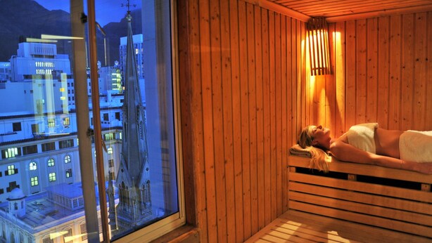 Una sauna de madera con un ventanal grande que da a una vista nocturna de la ciudad.