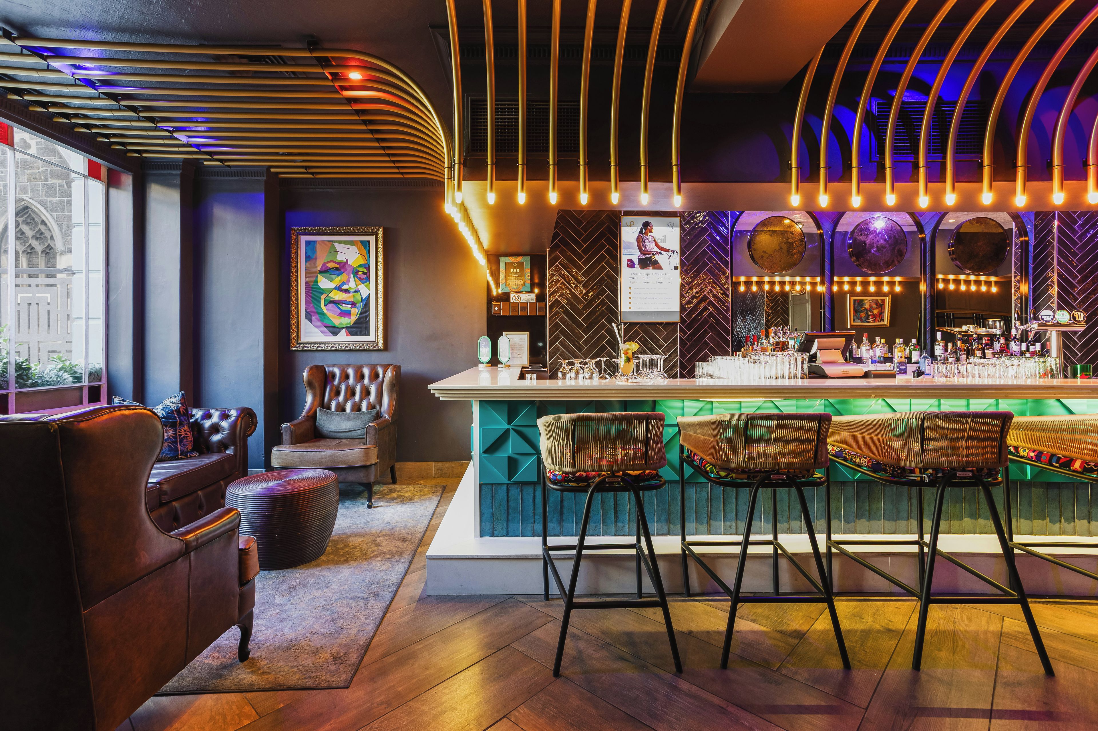 A bar area with a counter, stools, and a seating area with a couch and chairs.