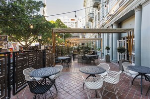 An outdoor patio area with tables and chairs, a pergola, and string lights.
