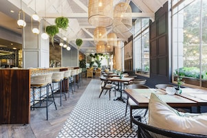 A restaurant interior with high ceilings, hanging wicker chandeliers, and a patterned floor.