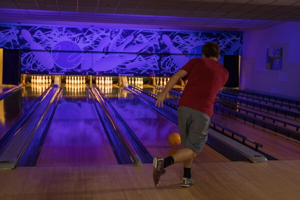 A bowling alley with lanes, pins, and a person bowling.