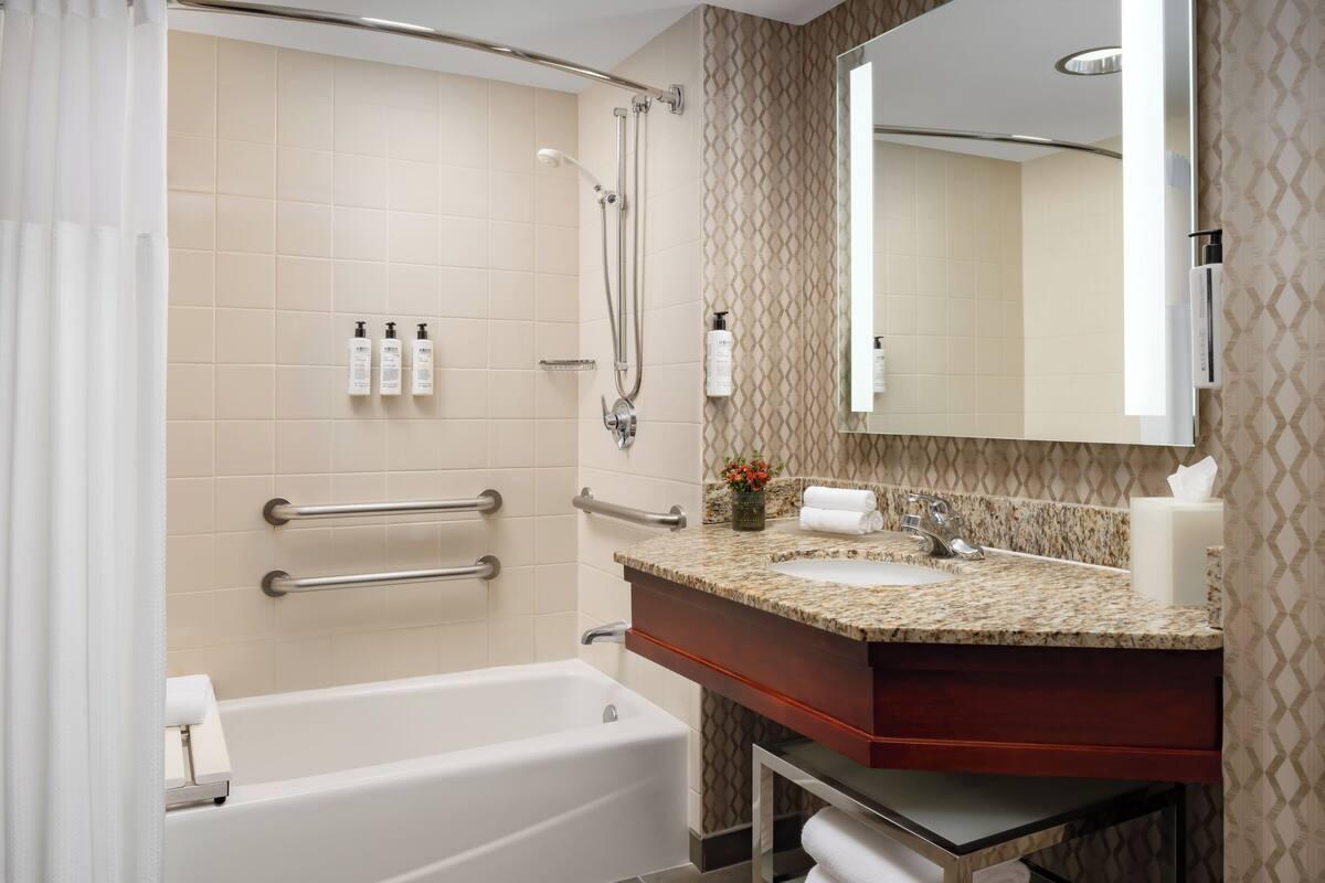 A modern bathroom with a bathtub, shower, and vanity with a sink.