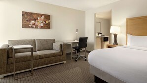 Ein Hotelzimmer mit einem Bett, einem Schreibtisch, einem Sessel und einer Wanddekoration.