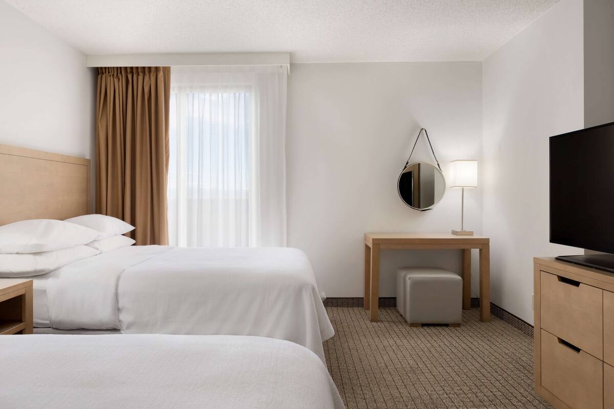 Une chambre d’hôtel avec deux lits, un bureau, une télévision et une lampe.