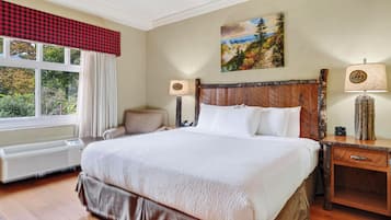Quarto de hotel com uma cama grande, uma cadeira, um quadro na parede e duas luminárias de cabeceira.