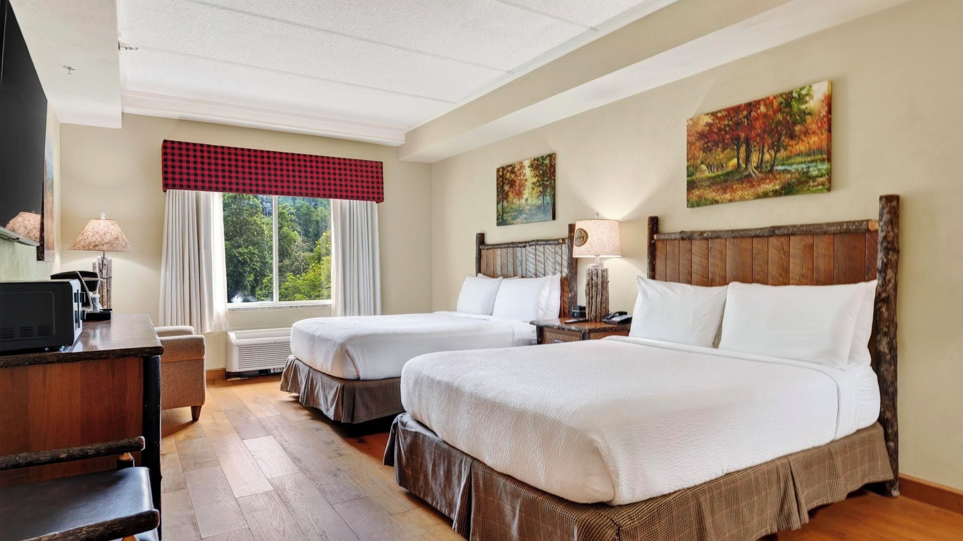 A hotel room with two beds, a desk, a TV, and a window with curtains.