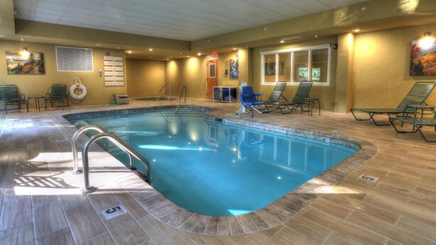 An indoor swimming pool with a tiled floor, a pool ladder, and lounge chairs around the perimeter. - The Appy Lodge (Gatlinburg)