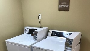 Two stacked front-loading washers in a corner with a wall-mounted sign indicating cycle times. - The Appy Lodge (Gatlinburg)