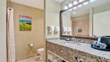 A bathroom with a shower, toilet, sink, and a large mirror.