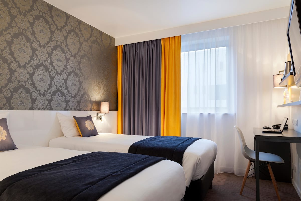 Habitación de hotel con dos camas, un escritorio y una silla.