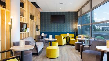 Interior de una cafetería moderna con paredes de madera, asientos cómodos y amplios ventanales.