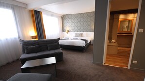 Una habitación de hotel con sofá, cama, una mesita y un espejo.