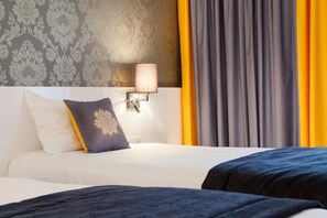 Une chambre d’hôtel avec un lit, une table de chevet avec une lampe et une fenêtre avec des rideaux.