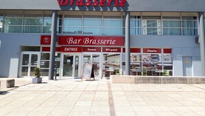 Un edificio con un letrero que dice “Bar Brasserie” y “ENTREE” señalando la entrada.