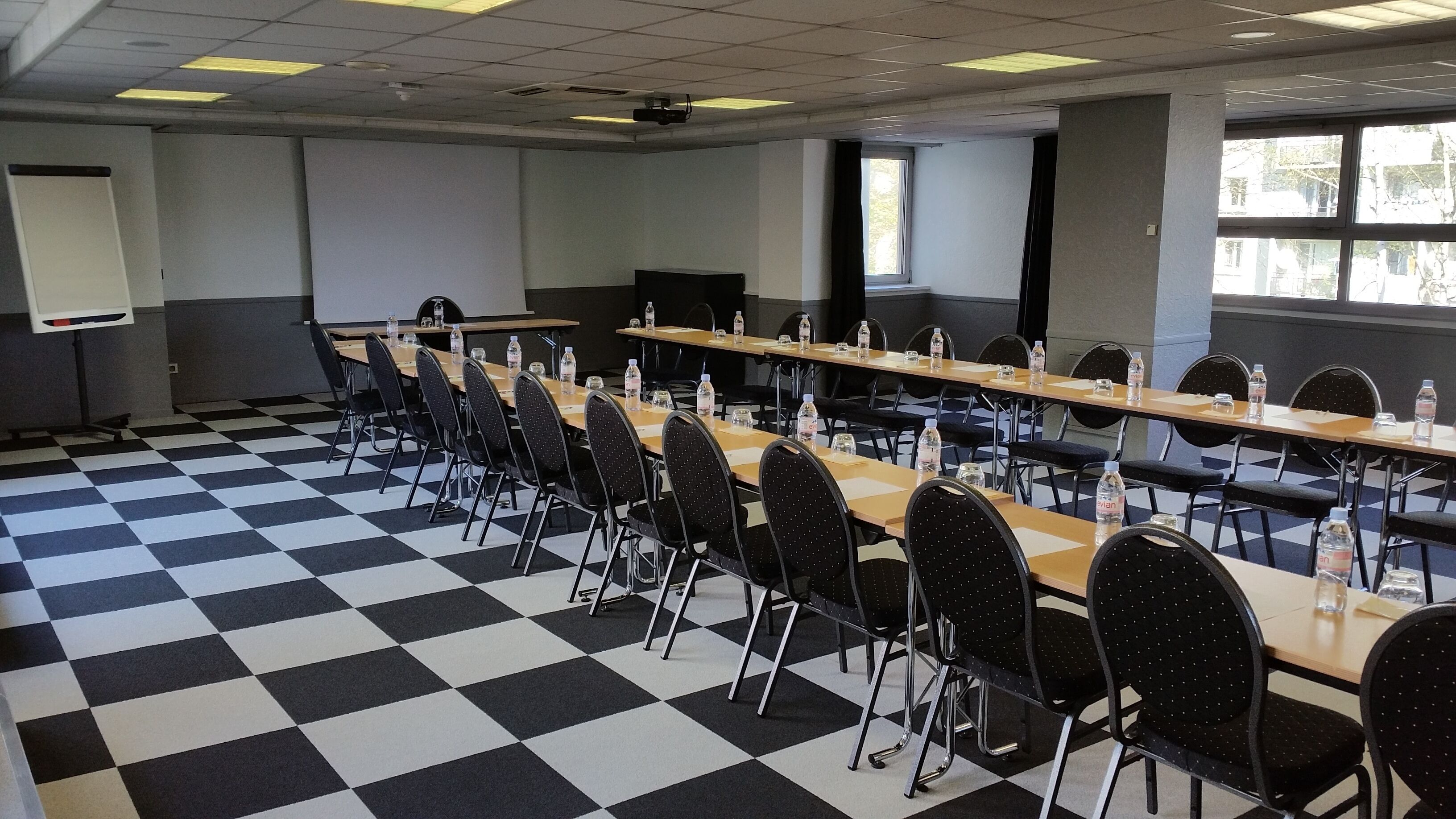 Une salle de conférence avec un sol à carreaux, de longues tables et des chaises.