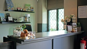 A reception desk with a glass jar, a ceramic dog figurine, and a vase of flowers. - Fletcher Hotel De Geulvallei (Valkenburg aan de Geul)