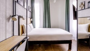 Une chambre d’hôtel moderne, dotée d’un grand lit, d’un bureau et d’une télévision.