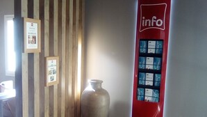 A hallway with striped walls, a large vase, and an 'info' sign with a directory. - ibis Orange Sud (Orange)