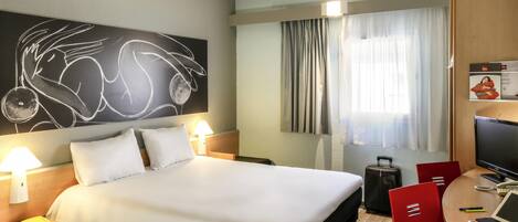 A hotel room with a bed, bedside lamps, a desk with a computer, a TV, and a large abstract painting on the wall.
