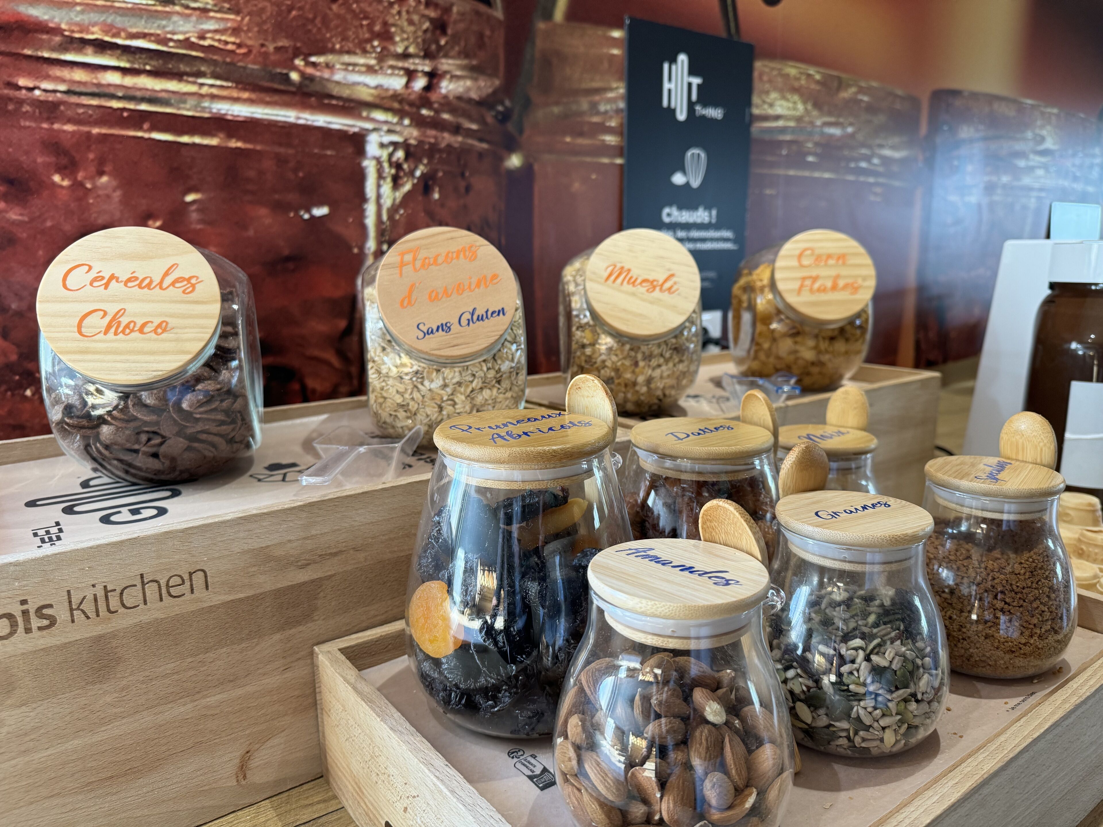 A display of various food items in glass jars with wooden lids, including cereals, flour, and nuts.