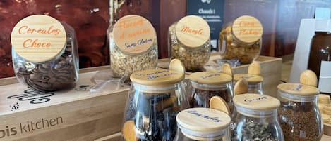 A display of various food items in glass jars with wooden lids, including cereals, flour, and nuts.
