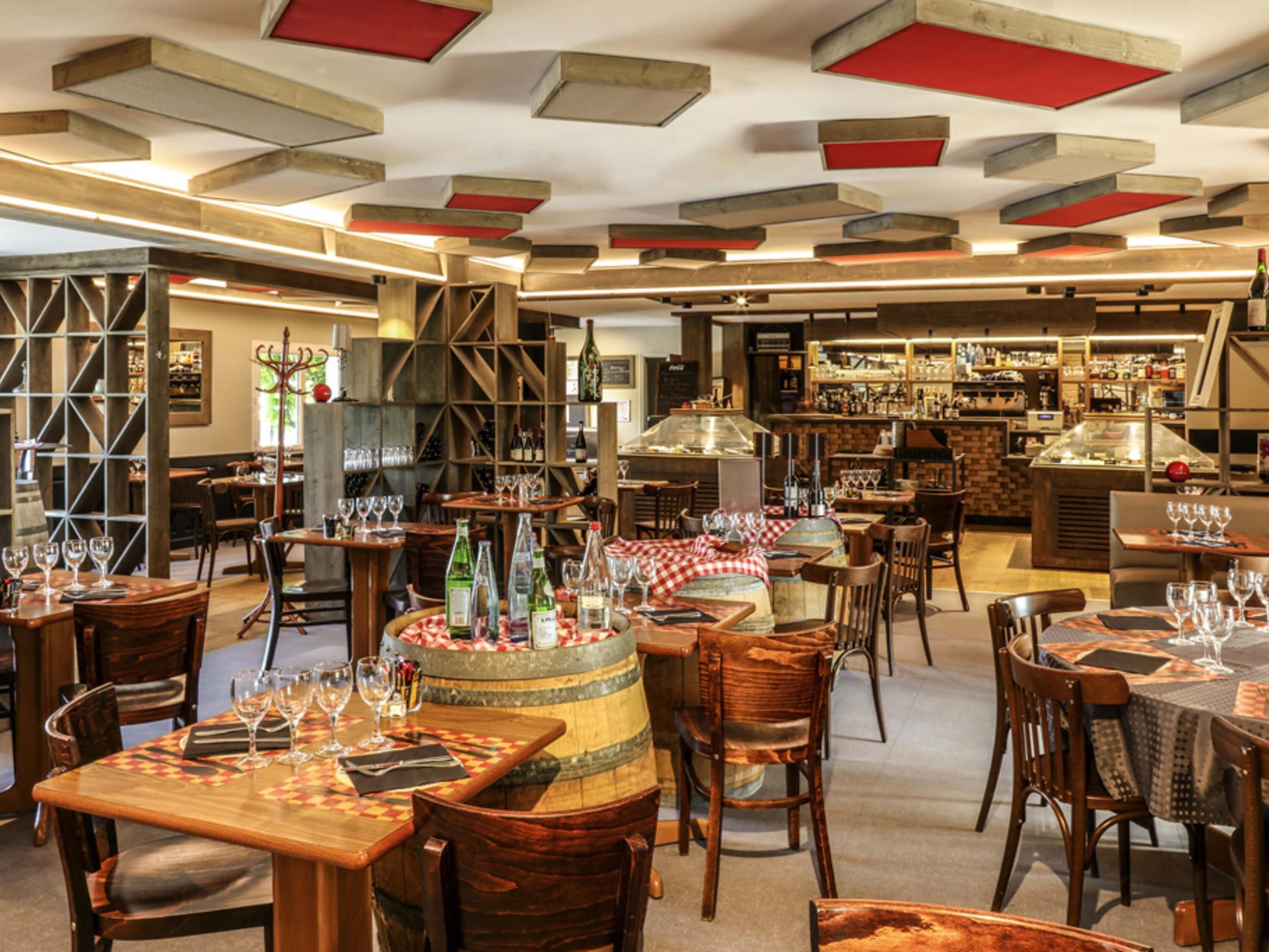 L’intérieur d’un restaurant, avec des tables et des chaises en bois, ainsi qu’un coin bar.
