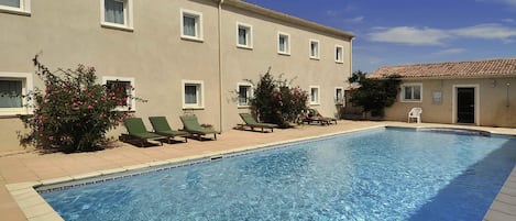 A swimming pool with lounge chairs and a building with multiple windows.