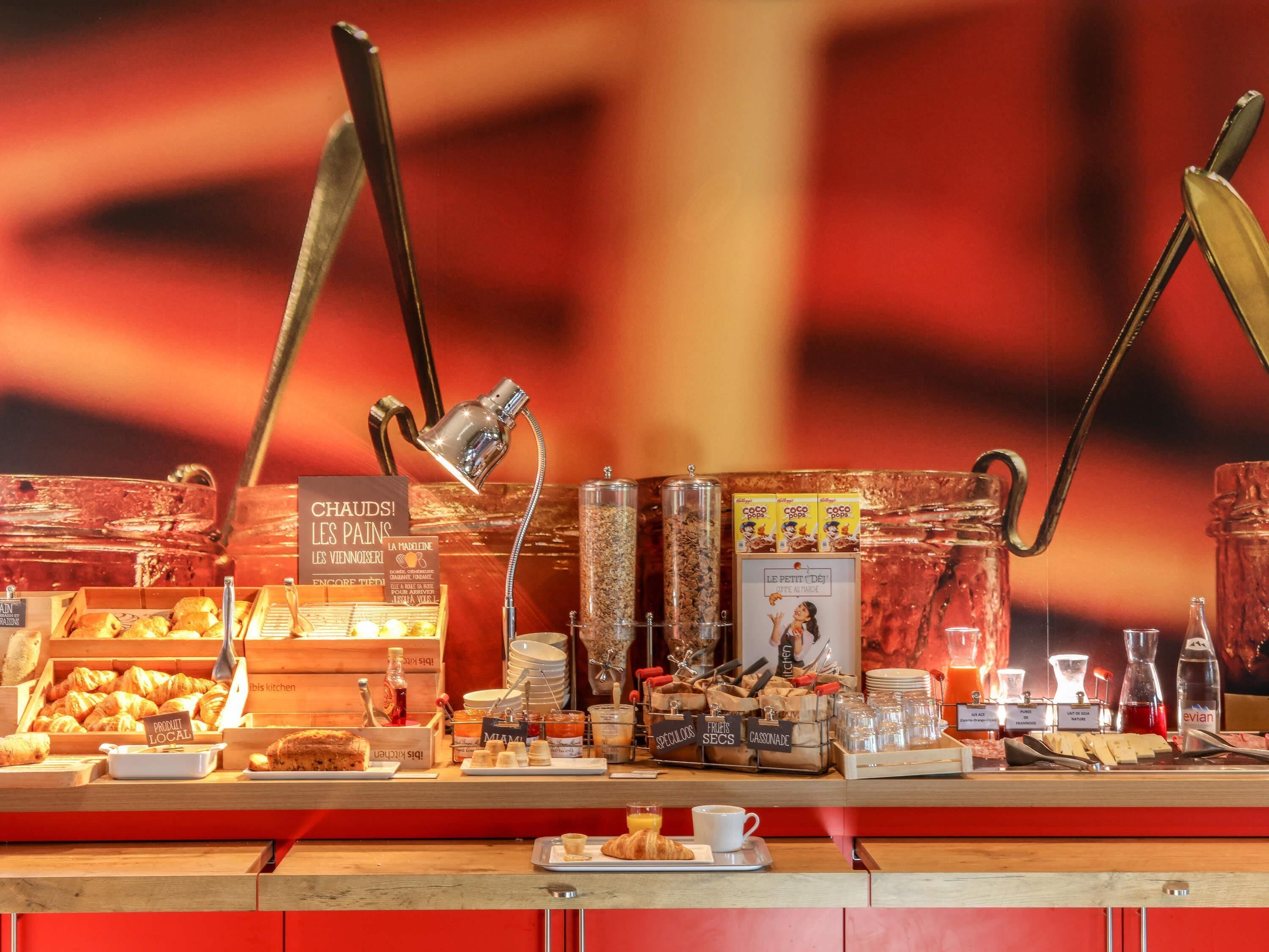 A breakfast buffet with various pastries, condiments, and a coffee station.