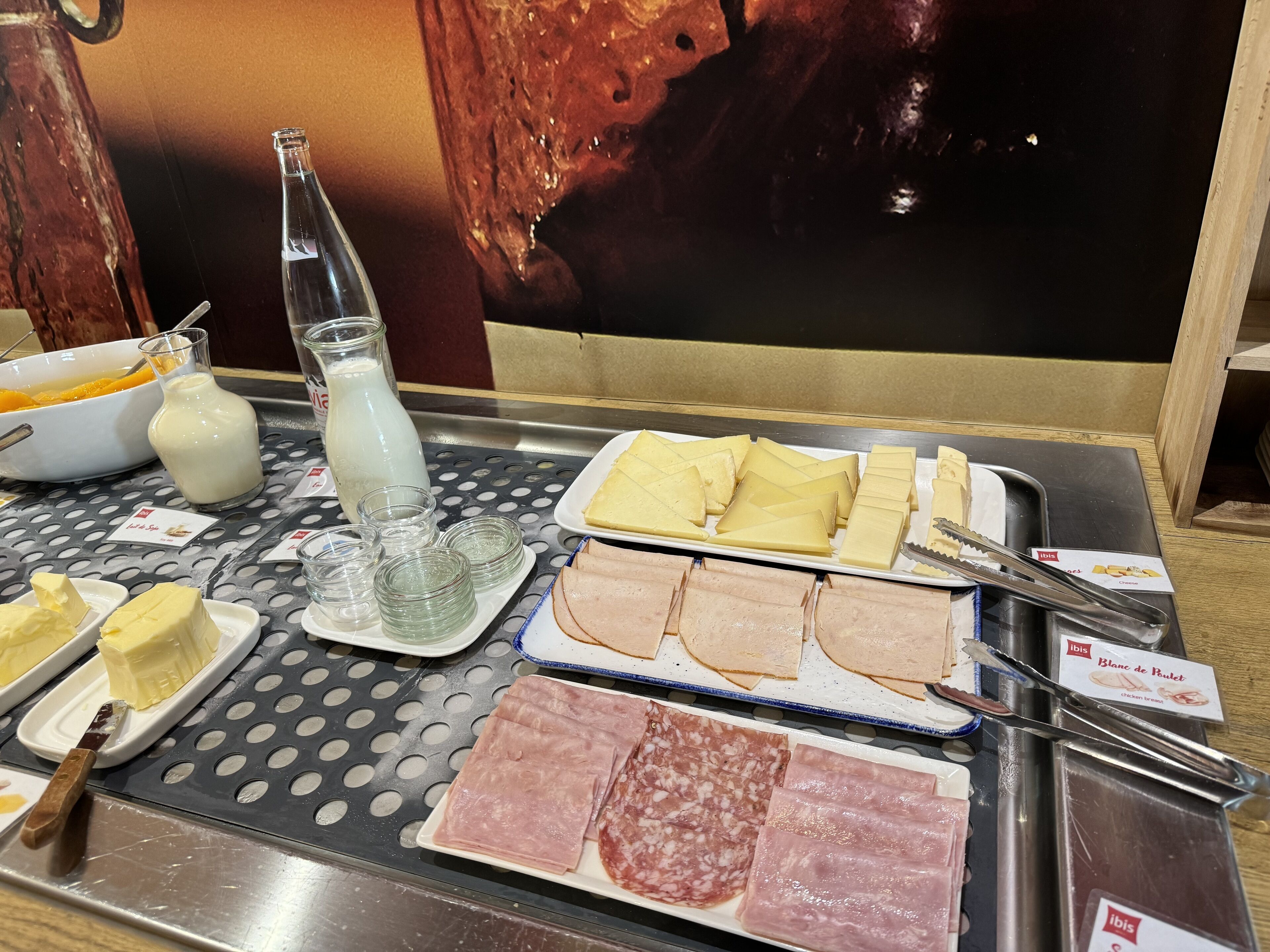 Une table de buffet proposant divers aliments, notamment du fromage, du jambon et une bouteille de lait.