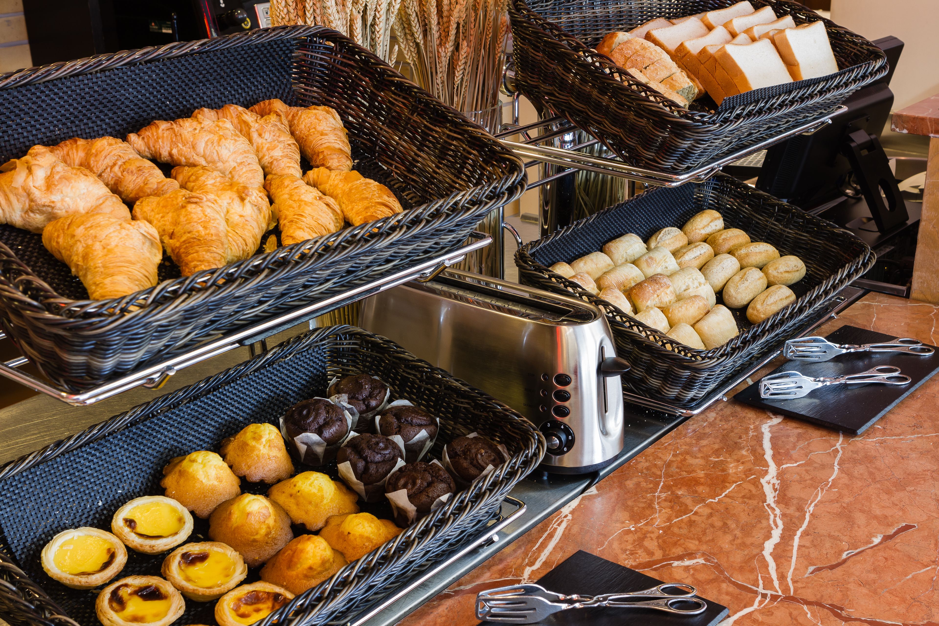 A buffet with various baked goods including croissants, bread, and pastries.