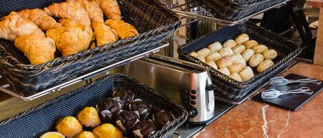 Un bufé con diversas opciones de panadería, incluyendo croissants, pan y pastelería.