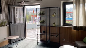 A modern living room with a sofa, a round table, a bookshelf, and a view of the outside. - ibis Leiria Fatima (Leiria)