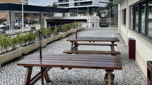 A rooftop terrace with picnic tables and potted plants, overlooking a modern building and a construction crane in the background. - ibis Leiria Fatima (Leiria)