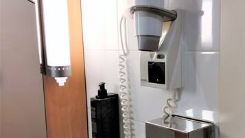 Un baño moderno con inodoro integrado, espejo, cafetera y secador de manos.