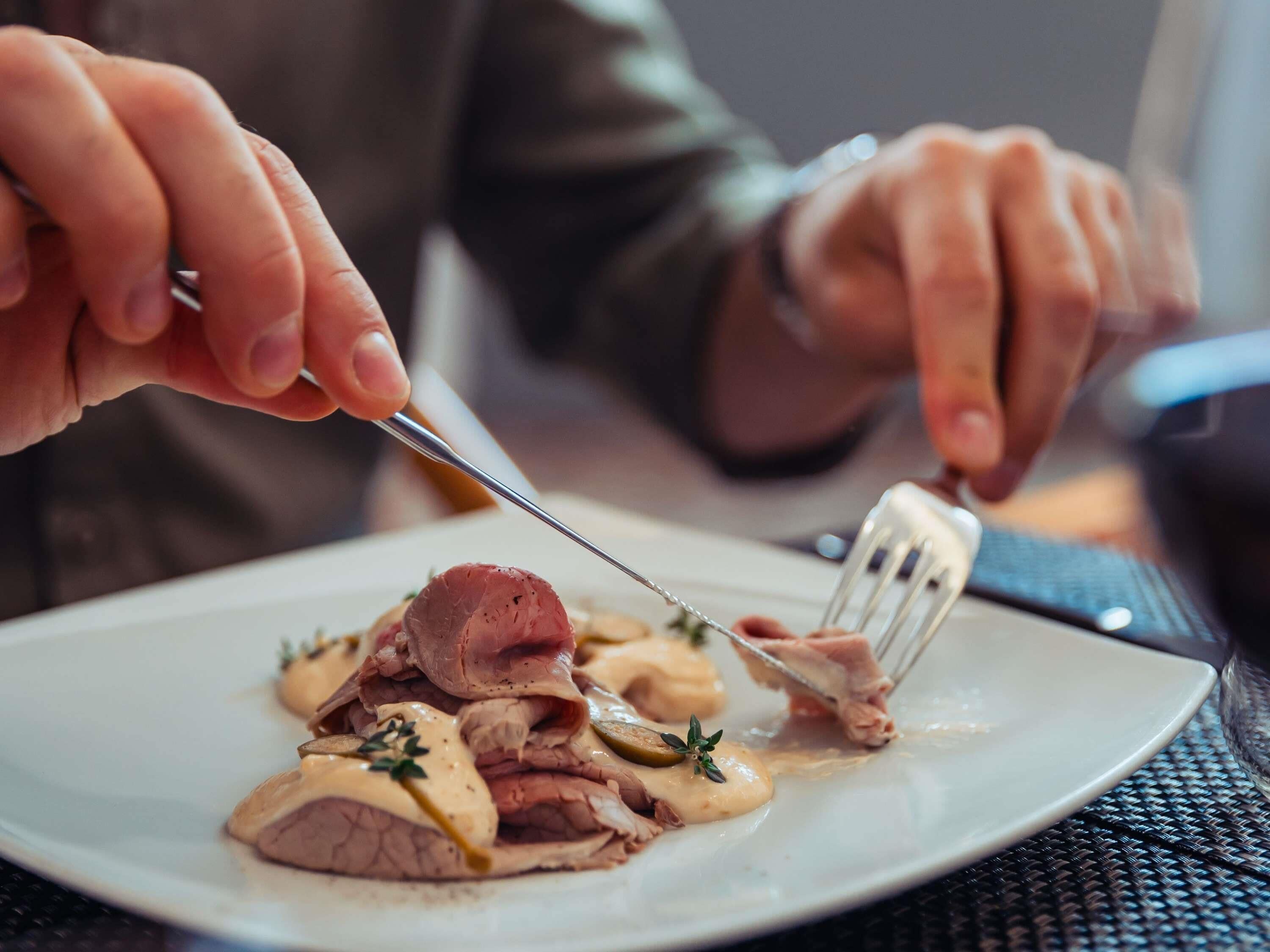A person cutting meat on a plate.